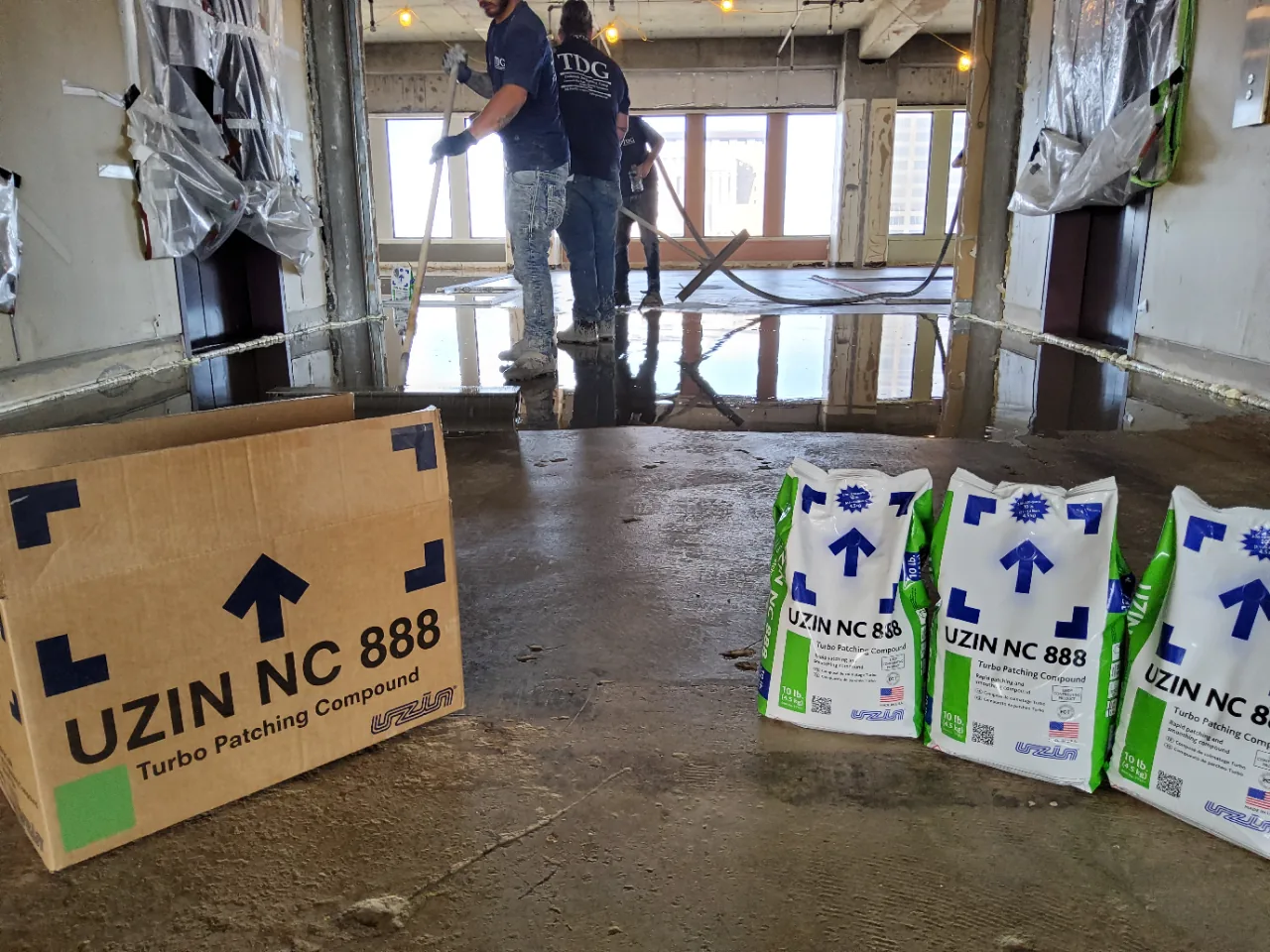 Bags of UZIN NC 888 self-leveling underlayment lined up on the concrete beside the pour